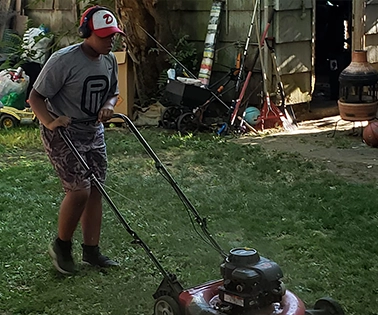 Worker raking fallen leaves into piles in a suburban front yard